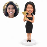 custom bobblehead figure woman in a black cocktail dress holding a gold trophy