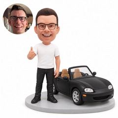 custom bobblehead figure man in a T-shirt and jeans standing beside a black convertible