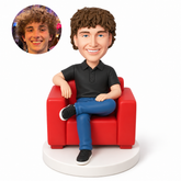 custom bobblehead figure male in a polo shirt and jeans seated with crossed legs in an armchair