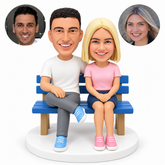 custom bobblehead figures couple seated on a bench with the man in a T-shirt and trousers and the woman in a T-shirt and short skirt