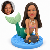 custom bobblehead figure female mermaid leaning forward with both hands on a rock and her tail raised behind her