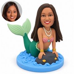 custom bobblehead figure female mermaid leaning forward with both hands on a rock and her tail raised behind her