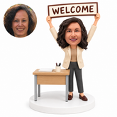 custom bobblehead figure woman standing at a desk holding a welcome sign overhead