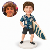 custom bobblehead figure man in a hawaiian shirt holding a diagonal surfboard with one hand in his pocket