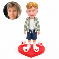 custom bobblehead figure boy standing among four LOVE letter hearts on a heart-shaped base
