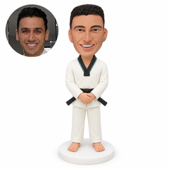 Custom male black-belt martial artist standing barefoot with both hands clasped low in front of his waist.
