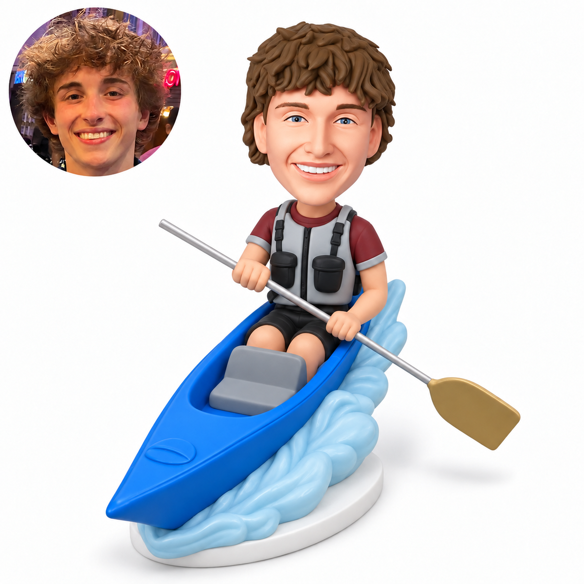 custom bobblehead figure male kayaker holding a single-bladed paddle across his lap in a blue kayak on a wave base