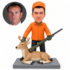 custom bobblehead figure male hunter holding a miniature rifle beside a reclining sculpted deer