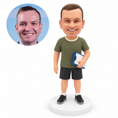 custom bobblehead figure male sports coach holding a clipboard at his left hip with his other arm relaxed at his side