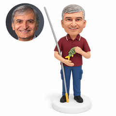 custom bobblehead figure man holding a fish with a fishing rod tucked under his arm and his other hand across his waist