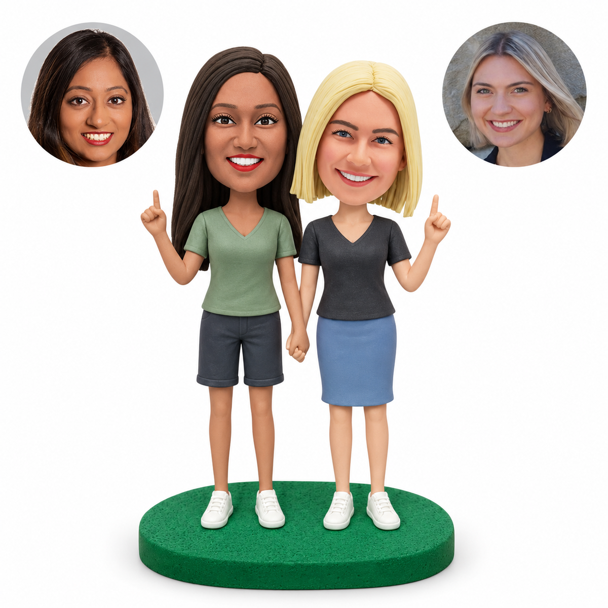 Two female clay bobblehead friends holding hands and raising one index finger each, with matching portrait photos