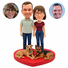 Custom clay couple bobbleheads holding hands with two fixed reclining dogs on a heart base and matching real portrait photos
