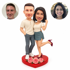 Custom clay casual couple on a red heart base with three pink roses, woman lifting one leg, with matching real photo portraits.