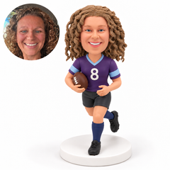 Female rugby player with her left leg forward, right arm holding one ball and open left hand at waist