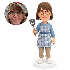 custom bobblehead figure woman in an apron holding a slotted spatula