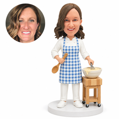 custom bobblehead figure woman in an apron whisking batter at a small kitchen trolley