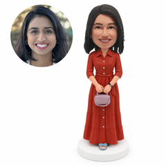 custom bobblehead figure woman in a long shirt dress holding a handbag with both hands