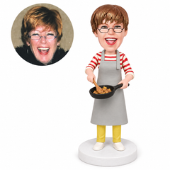 custom bobblehead figure woman in a long apron stirring food in a frying pan