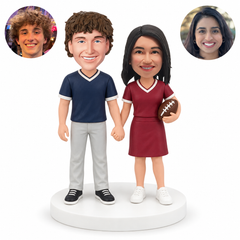 custom bobblehead figures football fan couple holding hands with woman holding one ball; original Bobblefigurine polymer clay heads with matching circular human portraits.