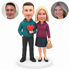 custom bobblehead figures hoodie couple with man holding heart and woman carrying handbag; original Bobblefigurine polymer clay heads and matching separate circular human portraits.