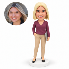 custom bobblehead figure woman in a v-neck blouse and trousers carrying a closed laptop with one hand in her pocket – original polymer-clay sculpture head and matching photo