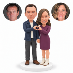 custom bobblehead figures couple in a field jacket and knee length sweater dress making a shared heart and holding hands