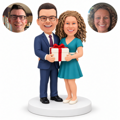 custom bobblehead figures couple in a suit and short dress embracing at the waist while holding one rectangular gift box - MGA-AC1420