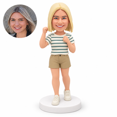 custom bobblehead figure woman in shorts raising her right fist beside her head and her left fist in front of her chest in a narrow staggered stance