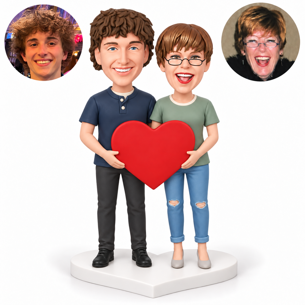 Two clay figurines share one large red heart with lower side grips, standing on a white heart-shaped base with matching male and female real portraits.