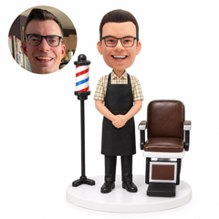 custom bobblehead figure barber in an apron beside a chair and barber pole