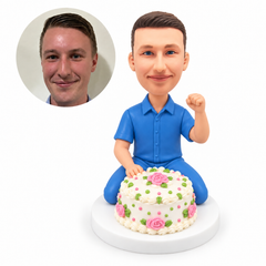 custom bobblehead figure man kneeling behind a decorated birthday cake