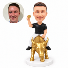 custom bobblehead figure man riding a standing golden bull while holding a coin aloft