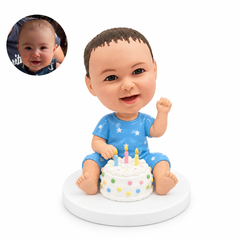 custom bobblehead figure baby sitting behind a decorated birthday cake