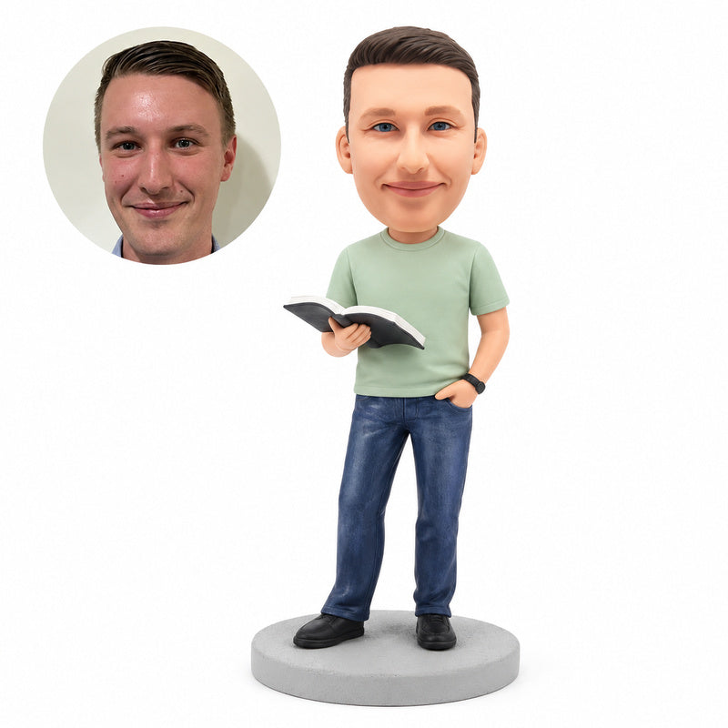 Custom clay bobblehead figure of a casual man in a sage T-shirt and jeans reading an open book