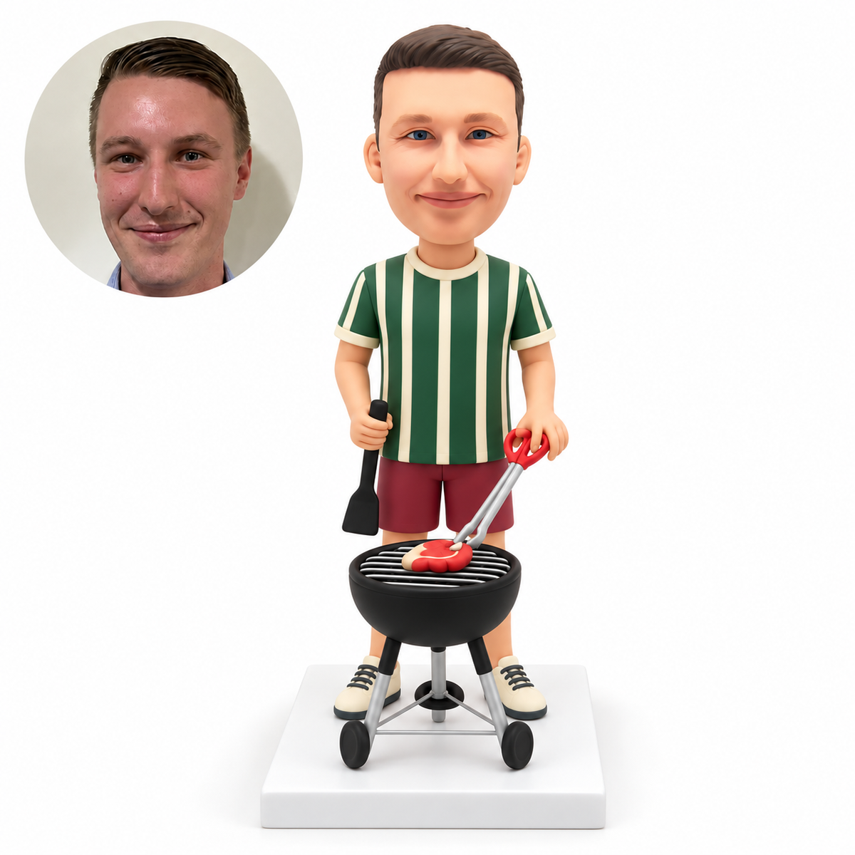 custom bobblehead figure man holding a spatula and scissor tongs over a wheeled kettle grill