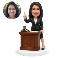 custom bobblehead figure female lawyer pointing upward behind a courtroom desk