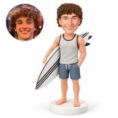 custom bobblehead figure male surfer carrying a surfboard under his arm with one hand in his pocket